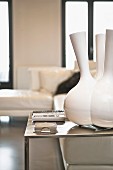 Designer-Vase mit mehreren Hälsen auf minimalistischem Stahltisch, Überecksofa unscharf im Hintergrund