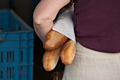 A woman holding three baguettes under her arm