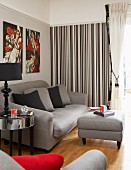 Grey sofa set with ottoman in living room with striped wallpaper on accent wall and pale grey wall