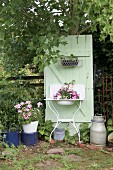 Planted, vintage washstand against mint-green board door in garden