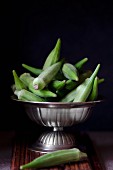 Fresh okra pods in a silver bowl