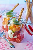 Melon and tomato salad with mozzarella and sesame seed sticks in preserving jars