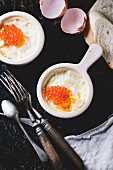 Baked eggs with red caviar, bread and vintage cutlery