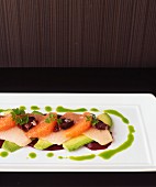 Wahoo sashimi on a bed of avocado and beetroot with grapefruit and olive fillets served with parsley sauce