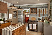 Rustic, country-house kitchen with free-standing, solid-wood island counter below pendant lamps with metal lampshades