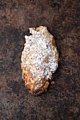 An almond croissant with icing sugar on a baking tray