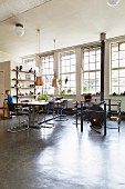 Dining table, cantilever chairs and vintage-style heating stove in loft-apartment interior with industrial glazing