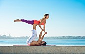 A couple in an acrobatic yoga position on the beach at San Diego