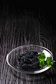 Black caviar with parsley in a glass bowl