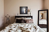 Mirror, bed and wire mesh tailors' dummy in modern bedroom