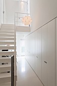 Fitted cupboards and white staircase in narrow foyer