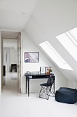 Black pouffe and chair at postmodern writing desk in attic room