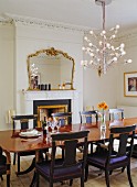 Original, antique dining table, reproduction chairs, whimsical designer chandelier and antique mirror above fireplace