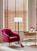 Magenta armchair, modern, elegant standard lamp and small, designer table in front of wooden louvre blinds on bay window