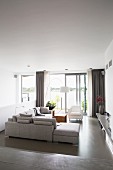 Hellgraue Ecksofa in elegantem Wohnzimmer mit grauem Epoxidharzboden und Seeblick