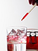 Raspberry juice being dropped into a glass of water with a pipette