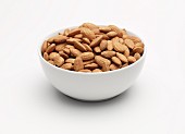 Unpeeled almonds in a white bowl