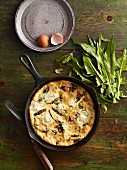 Ricotta frittata with sorrel in a pan on a wooden table