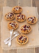 Shortbread tartlets with poppyseeds, toffee cream, cranberries and hazelnuts