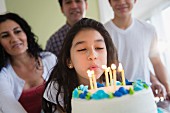 A girl with a birthday cake blowing out candles