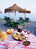 Paella mit Oliven, Brot und Sangria auf einem Tisch am Strand in Andalusien, Spanien