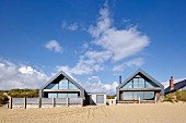 Camber Sands Beach Houses, Rye, United Kingdom. Architect: Walker and Martin, 2014; View of houses looking up from the beach