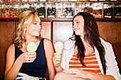 Two teenage girls eating ice cream in a cafe