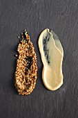 Two types of mustard on a grey slate surface