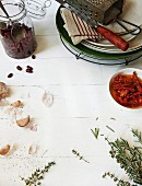 Zutatenstillleben mit roten Bohnen, Tomaten in Öl, Kräutern, Knoblauch und Geschirr