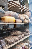 Käselaib und verschiedene Brote im Schaufenster einer Bäckerei (Close Up)