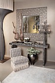 Arrangement in silver grey with sculptures, lamps, console table, mirror and easy chair with fringed trim