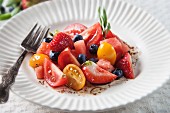 Red and yellow tomato salad with watermelon, strawberries, blueberries and balsamic vinaigrette