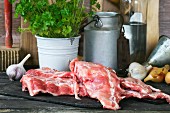 Raw pork ribs with vegetables and parsley on an old wooden table