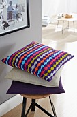 A colourful, knitted, homemade, striped cushion cover