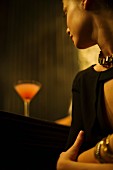 Frau sitzt mit Cocktail an der Bar