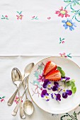 Fresh strawberries, violets and mint on a plate