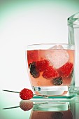 A cocktail with berries and ice cubes