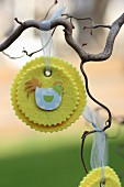 Hand-crafted, yellow felt rosettes with Easter motifs hanging from branch