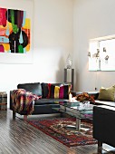 Schwarzes Ledersofa und Glas Couchtisch auf Orientteppich in minimalistischem Wohnraum