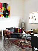 Black leather sofa and glass coffee table on Oriental rug in minimalist interior