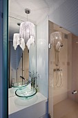 Elegantes Duschbad mit Glaswaschbecken, raumhohem Wandspiegel und Pendelleuchte mit Glitzerstoff
