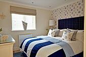 Schlafzimmer mit blau-weißer Bettwäsche und gemusterter Tapete