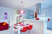 Red shell chairs around dining table against white kitchen counter in open-plan interior