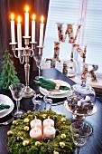 Advent calender and lit candles in candelabra on set table