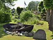 Traditionelles Holzboot auf Findlingen in sommerlichem Garten