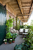 Loft-apartment balcony with weathered charm, comfortable seating area with rattan armchairs and climber-covered balustrade