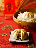 Meat filled dumplings and coins on a red tablecloth