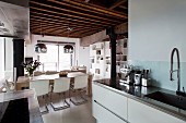 View from kitchen to dining area below mirrored spherical lamps hung from rustic wooden ceiling in loft apartment