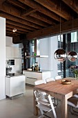 Dining area below mirrored, spherical lamps an open-plan kitchen in child-friendly loft apartment