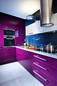 Modern fitted kitchen with purple fronts and stainless steel extractor hood